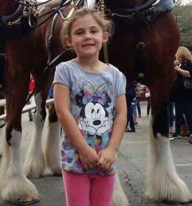 Le père demande à sa fille de poser devant les chevaux – s’rapprochant de la photo avec un fou rire