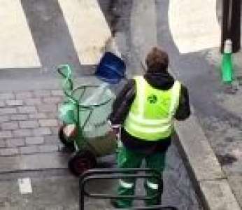 Un employé de la mairie de Paris remplit sa poubelle avec de l'eau