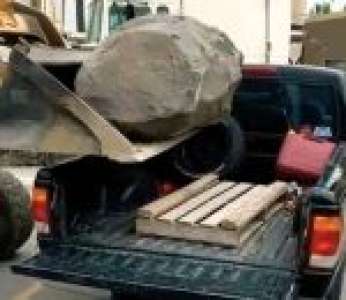 Régis charge un gros bloc de pierre dans un pick-up