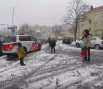 Un policier fait une bataille de boules de neige avec des enfants dans une rue (Pays-Bas)