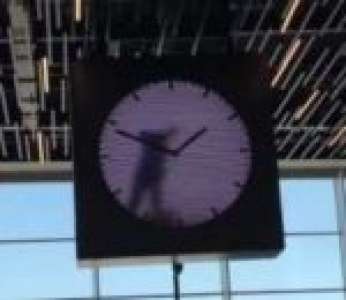 Un homme peint les aiguilles d'une horloge originale à l'aéroport d'Amsterdam (Pays-Bas)