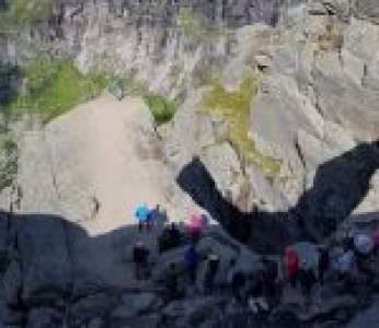 Des randonneurs font la queue pour faire une photo sur le rocher Trolltunga (Norvège)