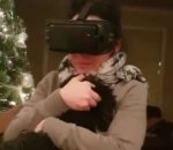 Une femme teste la réalité virtuelle avec un chien dans les bras